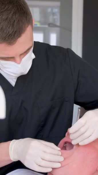 Een tandarts installeert moderne tandheelkundige implantaten op een oudere man. Tandheelkundige behandeling op hoge leeftijd. Gezondheidszorg. Verticale video - Video