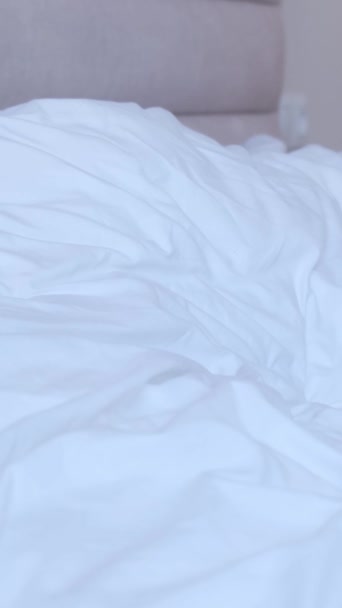Egy nagyon fáradt, öltönyös fiatalember ráesik egy fehér ágyra. Fáradt üzletember munka után pihen. Függőleges videó - Felvétel, videó