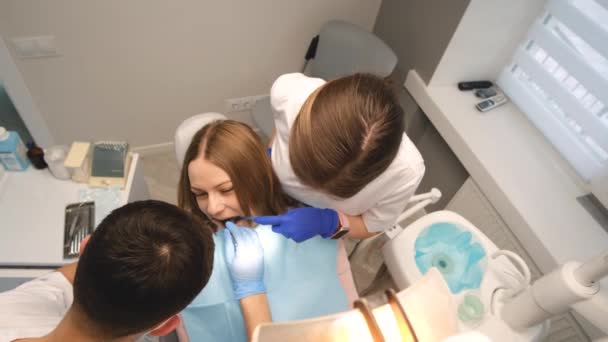Zwei Zahnärzte in einer Zahnklinik, die eine Patientin betreuen. Schmerzfreie Zahnbehandlung in einer modernen Klinik. 4k-Video - Filmmaterial, Video