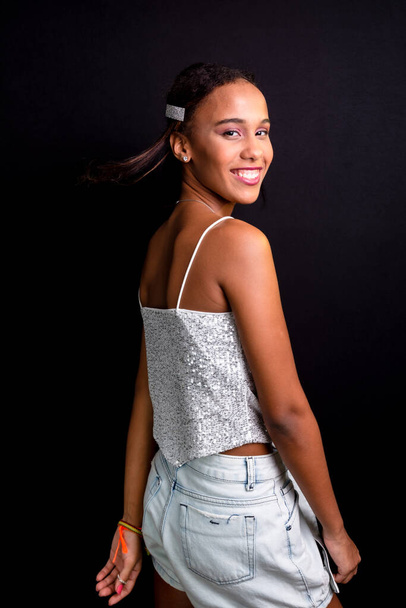 Portret van een tienermeisje, lachend, mooi, met witte kleren aan. Geïsoleerd op zwarte achtergrond. - Foto, afbeelding