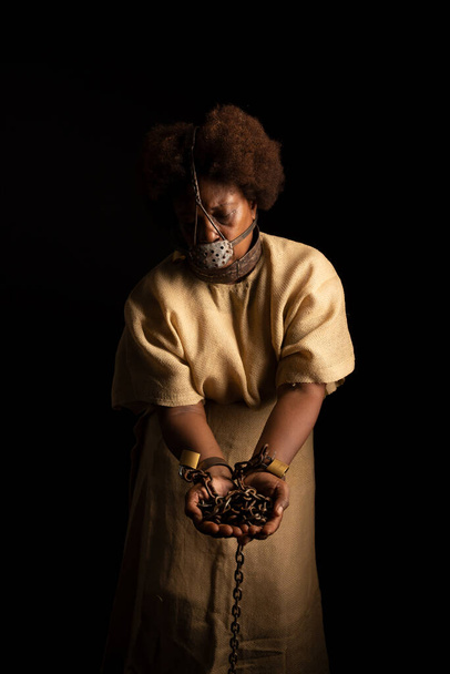 Portrait of a black woman in chains and with an iron mask on her face holding chains. Slave Anastacia. Slavery in Brazil. - Foto, Imagen