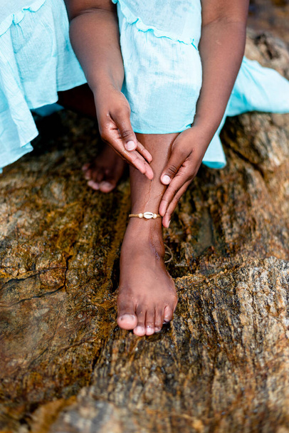 Жінка в світло-блакитному вбранні, сидячи на березі скелі, плескає ноги. Ріо-Вермехо-Біч, Сальвадор, Бразилія. - Фото, зображення