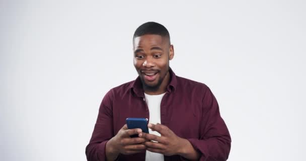 Lotto, cash and black man winning on a phone in celebration isolated in a studio white background. Wow, winner and young person happy or excited for money bonus online from mobile app or internet. - Footage, Video