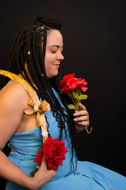 Beautiful woman with braids in her hair holding a hula hoop and smelling a red rose. Positive person. Isolated on black background. - Fotografie, Obrázek
