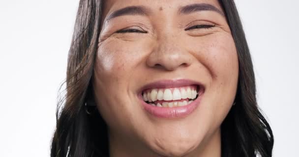 Face, funny and Asian woman with a smile, humor and girl laughing on white studio background. Portrait, model and Japanese person with happiness, freedom and joke with self love, laughter or carefree. - Materiaali, video