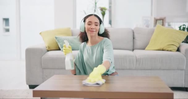 Housekeeping, headphones and woman cleaning the table with detergent, cloth and gloves at home. Female maid, cleaner or housewife dancing and wipe the furniture for dust, dirt or bacteria with music - Footage, Video