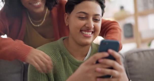 Phone, hug and an lgbt couple laughing together in their home while browsing a social media app. Gay, love and comedy with happy lesbian women looking at memes on a mobile for fun or romantic bonding. - Footage, Video
