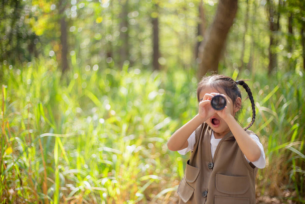 ハッピーリトルアジアの女の子は,公園の双眼鏡で子供を笑顔で見ています. 旅行と冒険のコンセプト。 フリーダム,休暇 - 写真・画像