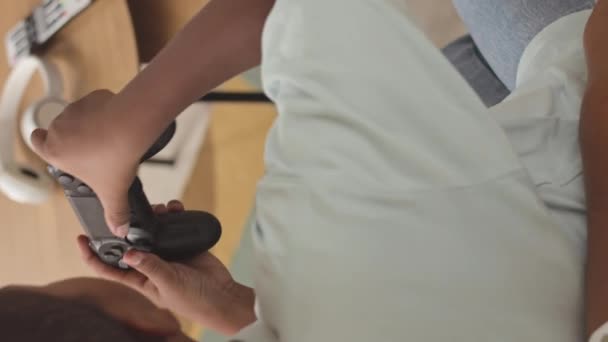 Vue arrière verticale prise de vue de afro-américain entre garçon utilisant contrôleur tout en jouant à un jeu vidéo à la maison pendant les loisirs - Séquence, vidéo