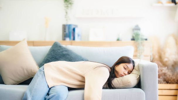 Azjatka odpoczywająca w domu na kanapie, zmęczona po pracy, pozbawiona energii lub przepracowana, zbyt zmęczona i pozbawiona motywacji - Zdjęcie, obraz