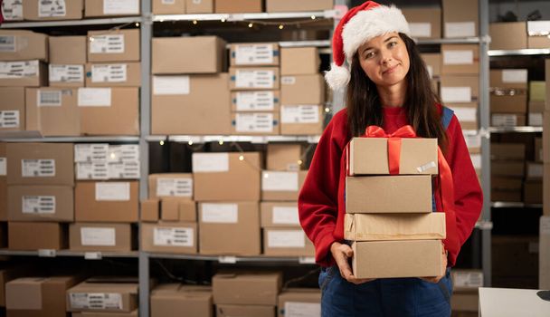 Retrato del trabajador del almacén sosteniendo cajas de cartón sonriendo felizmente y mirando a la cámara mientras hace envíos y entregas Paquetes y regalos de Navidad. Copiar espacio - Foto, imagen