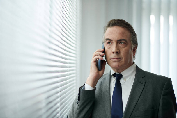 Portret van ongelukkig volwassen zakenman praten over de telefoon met collega - Foto, afbeelding