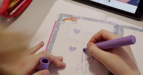 The teenager is at home drawing at the table, the childrens room in pink colors. Take homework lessons. Teenager with headphones writes on notebook and uses tablet gadget for internet. - Кадры, видео