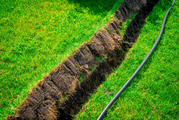 Auto-instalação de irrigação com um aspersor retrátil no relvado acabado. Colocação de tubos de água com pulverizadores sob o gramado para irrigação. - Foto, Imagem