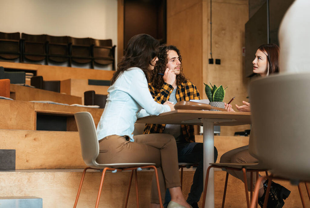 Jonge en aantrekkelijke college vrienden bespreken over hun laatste examen op kantoor - Foto, afbeelding