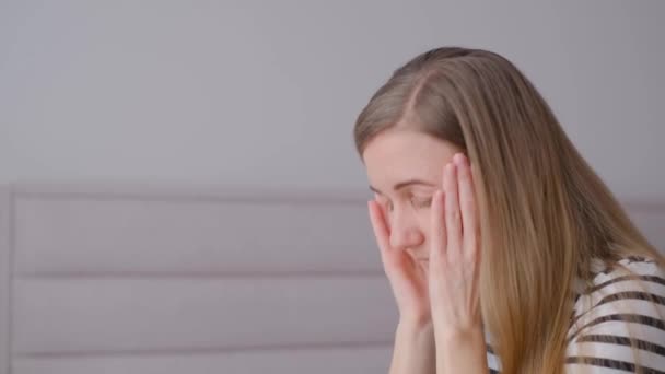 Eine Frau mit gesenktem Kopf und vor ihrem Gesicht verschränkten Händen. Ein Blick auf Verzweiflung, Depression, Migräne oder Kopfschmerzen. - Filmmaterial, Video