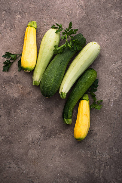 Assortment of different color of fresh zucchini on brown table - Photo, Image