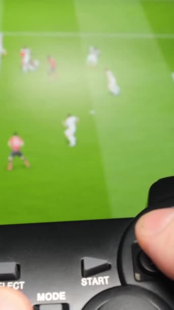 Παίζοντας ένα παιχνίδι ποδοσφαίρου στον υπολογιστή με τη βοήθεια ενός χειριστηρίου. Κοντινό πλάνο του αρσενικού παιχνιδιού παιχνιδιού χέρι στην οθόνη του υπολογιστή. Παίκτης υπολογιστών παιχνιδιού. Κάθετη βίντεο - Πλάνα, βίντεο