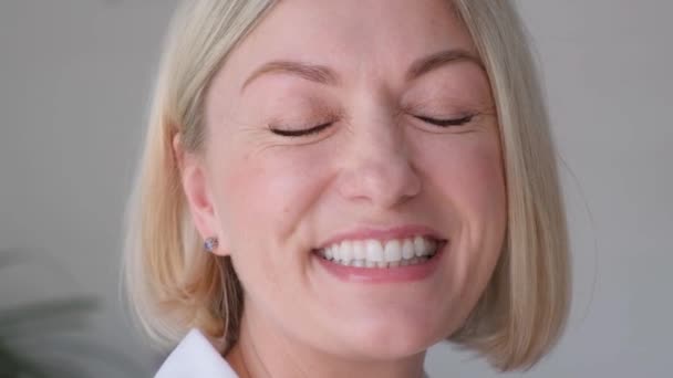 Porträt einer schönen 40-jährigen Blondine von europäischem Aussehen, die in die Kamera lacht. Vertikales Video - Filmmaterial, Video