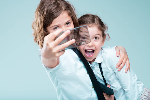 Μοντέρνα νεαρά κορίτσια στην επιχείρηση ντύσιμο snap selfies, λαμβάνοντας υπόψη τους σε απευθείας σύνδεση εμφάνιση και τη φήμη με τα τηλέφωνα αιχμής - Φωτογραφία, εικόνα