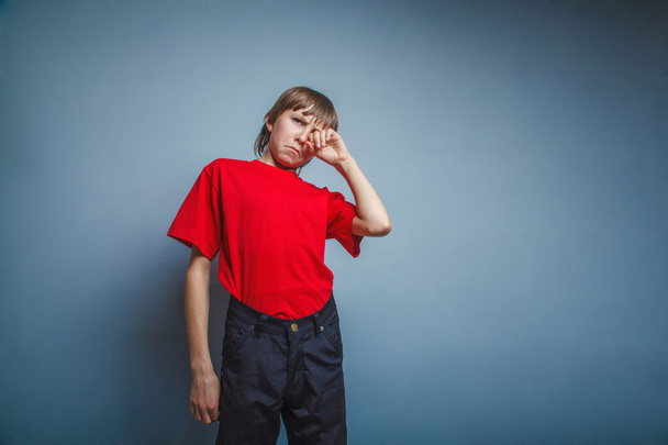 Boy, teenager, twelve years in  red T-shirt, hand wipes tears, s - Фото, зображення