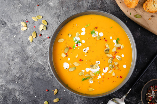 Тыквенный суп, вкусная домашняя тыква, сладкий картофель или морковный суп в миске на темно-сельском фоне - Фото, изображение