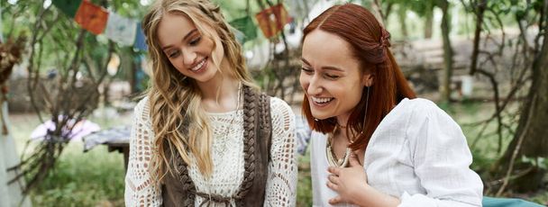 smějící se ženy ve stylových šatech tráví spolu čas v útulku venku, prapor - Fotografie, Obrázek