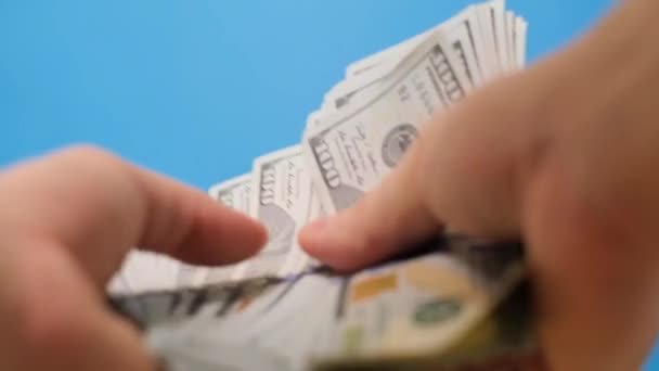 Detailní záběr Evropana, jak počítá peníze v dolarech na modrém pozadí. Rodinný rozpočet, hotovost. Svislé video - Záběry, video