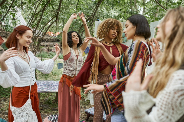 stylish multiethnic friends with closed eyes dancing outdoors in modern retreat center - Foto, Bild