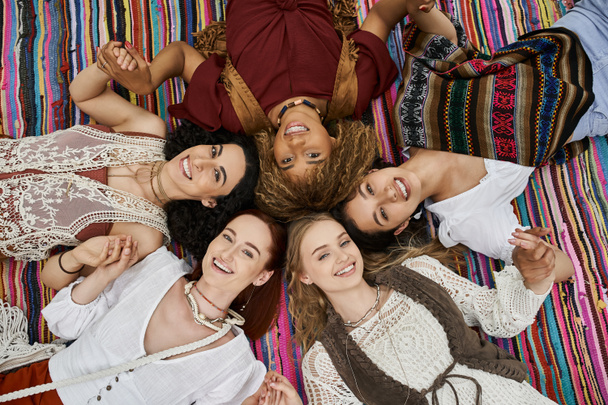 κορυφαία άποψη των χαρούμενων διαφυλετικών γυναικών κοιτάζοντας κάμερα σε κουβέρτα στο κέντρο υποχώρησης - Φωτογραφία, εικόνα