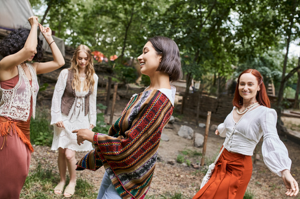 positive brunette woman in stylish outfit dancing near multiethnic friends in retreat center - Foto, immagini