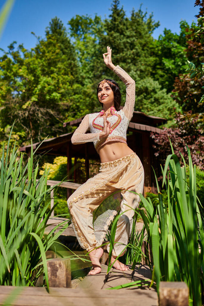 Kaygısız ve zarif Hintli kadın, güneşli bir günde yaz parkında dans ediyor. - Fotoğraf, Görsel