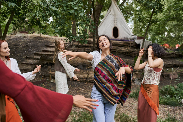 Lächelnde Frau tanzt zusammen mit multiethnischen Freunden im Sommer im Retreat Center - Foto, Bild