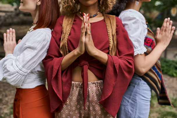 abgeschnittene Ansicht von interrassischen Frauen in stylischer Kleidung, die im Retreat Center eine Geste betender Hände machen - Foto, Bild