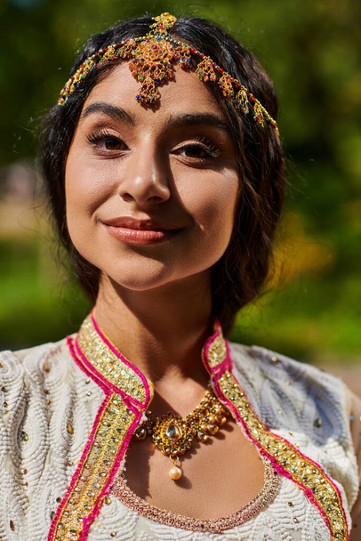 ritratto di giovane donna indiana bruna in autentico abbigliamento sorridente alla macchina fotografica nella giornata estiva nel parco - Foto, immagini