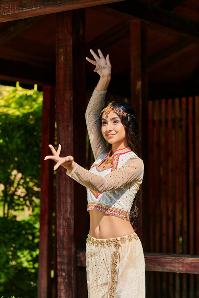 mujer india despreocupada y elegante en traje tradicional bailando en el día de verano en el parque - Foto, imagen