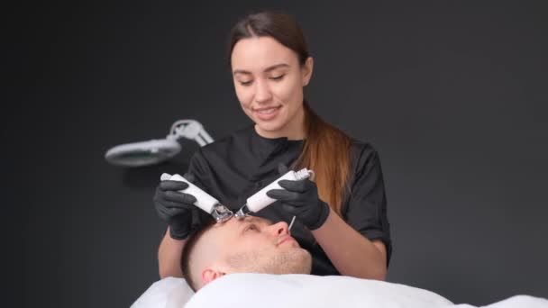 A female cosmetologist performs a cavitation procedure. Rejuvenation of facial skin for men. - Footage, Video