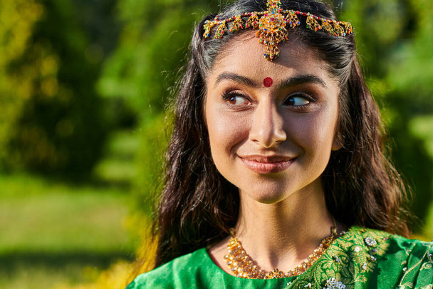 muotokuva kaunis ja hymyilevä intialainen nainen bindi ja matha patty seisoo ulkona - Valokuva, kuva