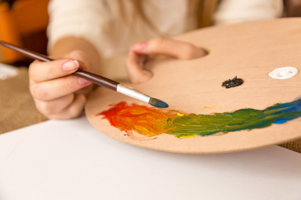 woman holding paintbrush and choosing paint on pallet - 写真・画像