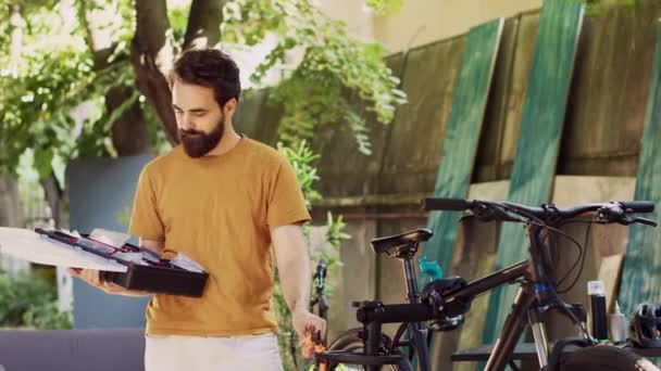 Gezonde atletische blanke man draagt zijn gespecialiseerde gereedschapskist in huis tuin voor fiets onderhoud. Sport-liefhebbende actieve mannelijke fietser regelen van professionele apparatuur buiten voor fiets reparatie. - Video