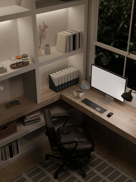Draufsicht auf ein modernes Luxus-Home-Office bei Nacht mit einer Computer-Weißbildschirm-Attrappe auf einem Tisch vor dem Fenster und großen eingebauten Regalen. 3D-Renderer, 3D-Illustration - Foto, Bild
