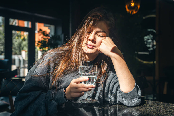 Приваблива молода жінка зі склянкою води в кафе в сонячний день. - Фото, зображення
