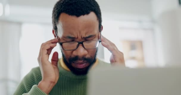 Man, remote work and headache at laptop from stress, burnout and brain fog. Face of confused african freelancer with glasses, eye strain and pain of frustrated challenge at computer in home office. - Footage, Video