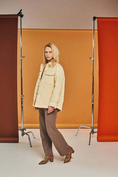 jesień moda koncepcja, blondynka kobieta jesienią strój i zwierząt druk buty pozowanie na pomarańczowym tle - Zdjęcie, obraz