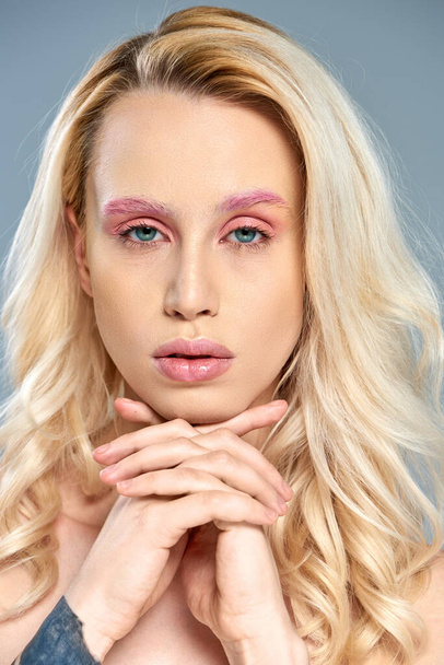 Μοντέλο με τατουάζ με ροζ μακιγιάζ ματιών και ξανθά μαλλιά που ποζάρουν σε γκρι φόντο, θηλυκή ομορφιά - Φωτογραφία, εικόνα