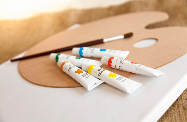 масляные краски в трубах и кисти, лежащие на деревянном поддоне
 - Фото, изображение