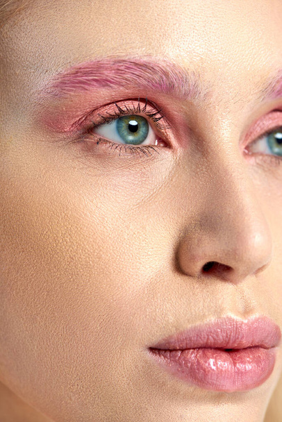 λεπτομερής φωτογραφία της νεαρής γυναίκας με μπλε μάτια και ροζ μακιγιάζ μάτια κοιτάζοντας μακριά, κοντινό πλάνο - Φωτογραφία, εικόνα