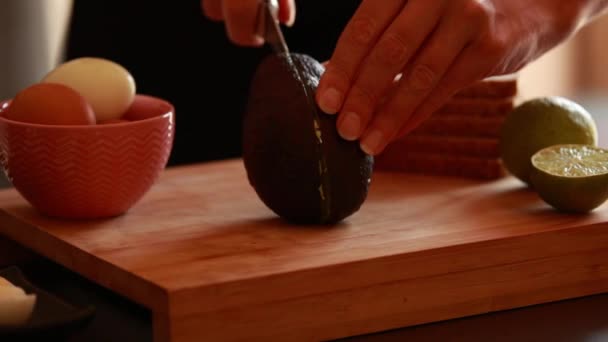 mulheres mãos preparando abacate para comer de perto na tábua de madeira em casa - Filmagem, Vídeo
