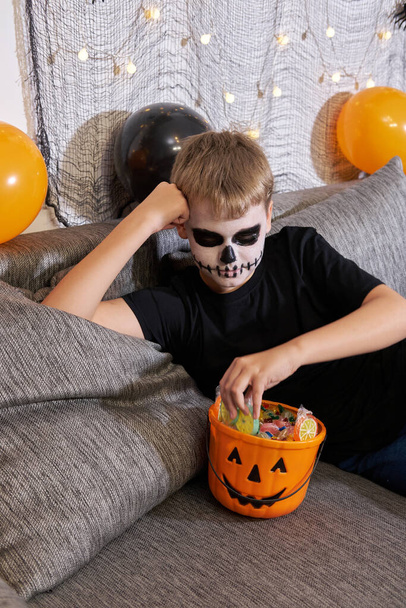 Dítě vyndá cukroví z vědra na Halloween. Chlapec slaví Trick or Treat. - Fotografie, Obrázek