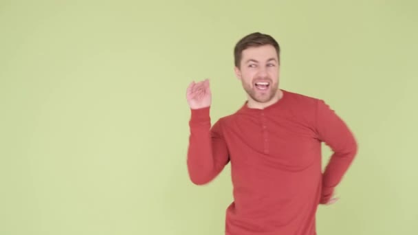 Ένας νεαρός με πορτοκαλί πουλόβερ χορεύει περίεργα απομονωμένος στο βάθος του στούντιο. Κάθετη βίντεο - Πλάνα, βίντεο